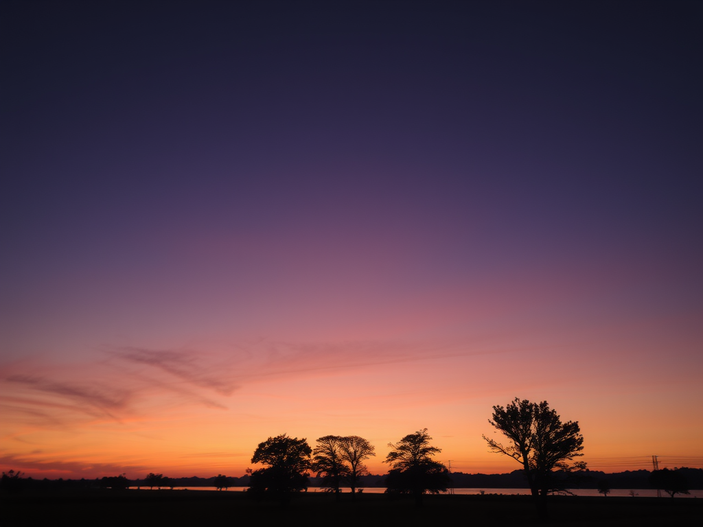 Céu ao amanhecer com gradientes de roxo e rosa, árvores em silhueta na linha do horizonte.
