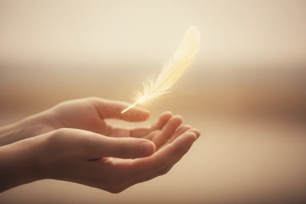 Hands releasing a feather, symbolizing the act of stopping trying to be perfect.