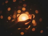 Mãos segurando uma luz, simbolizando a esperança nos dias mais escuros.
