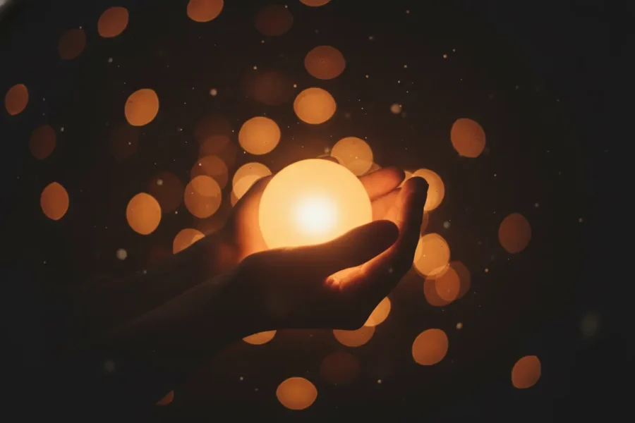 Mãos segurando uma luz, simbolizando a esperança nos dias mais escuros.