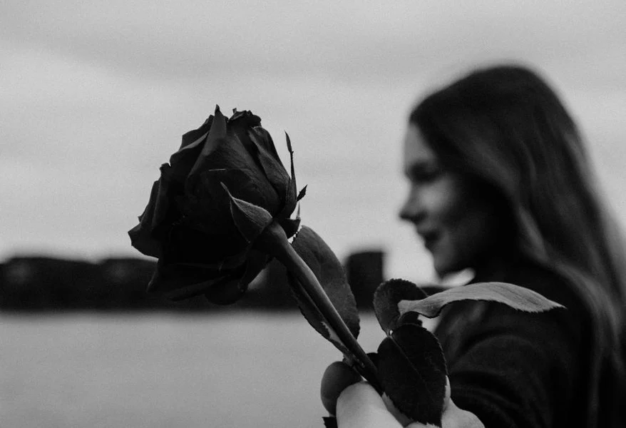 romantic woman holding hand on anonymous boyfriend giving flower at lakeside
